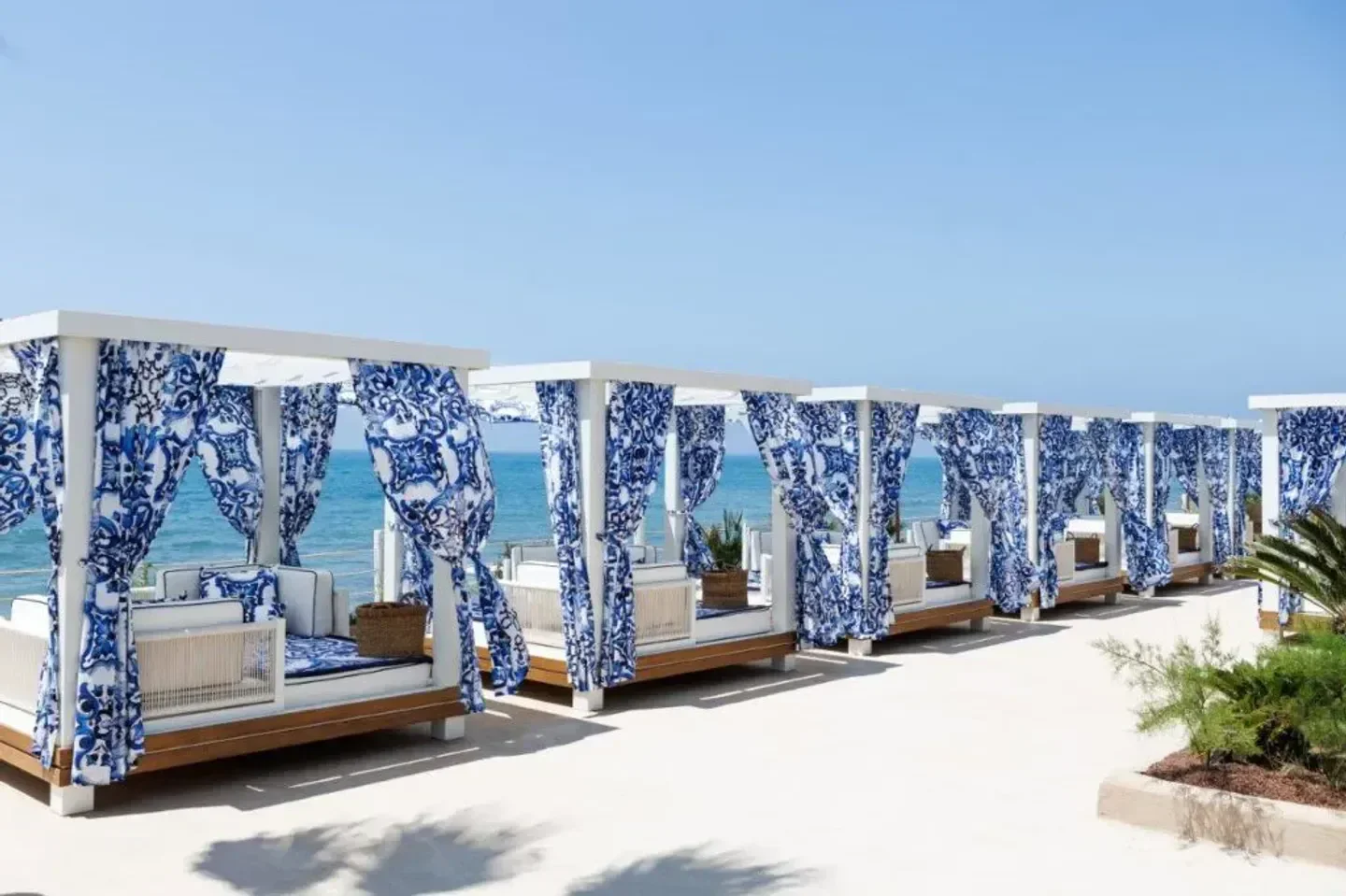Beach cabanas at La Cabane in Marbella, with patterned curtains and ocean views.