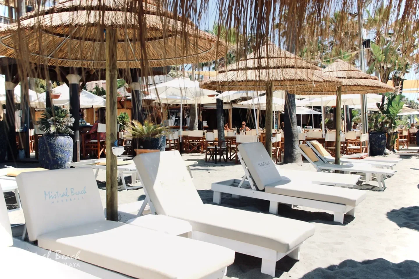 Relaxing beach scene at Mistral Beach in Marbella with straw umbrellas and sunbeds