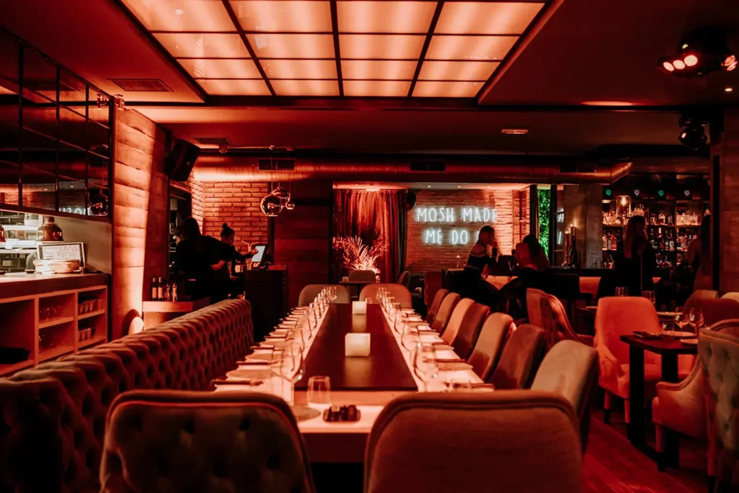 Stylish interior dining at Mosh restaurant in Marbella, featuring a long table and cozy seating.