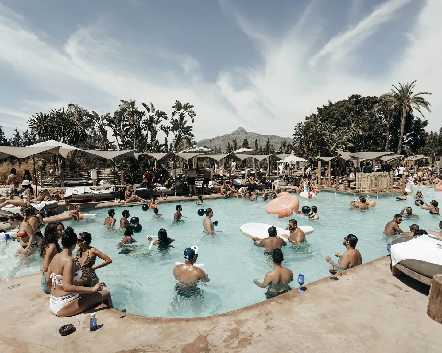 Pool party at Nao Beach Club in Marbella, with people enjoying sunny day.