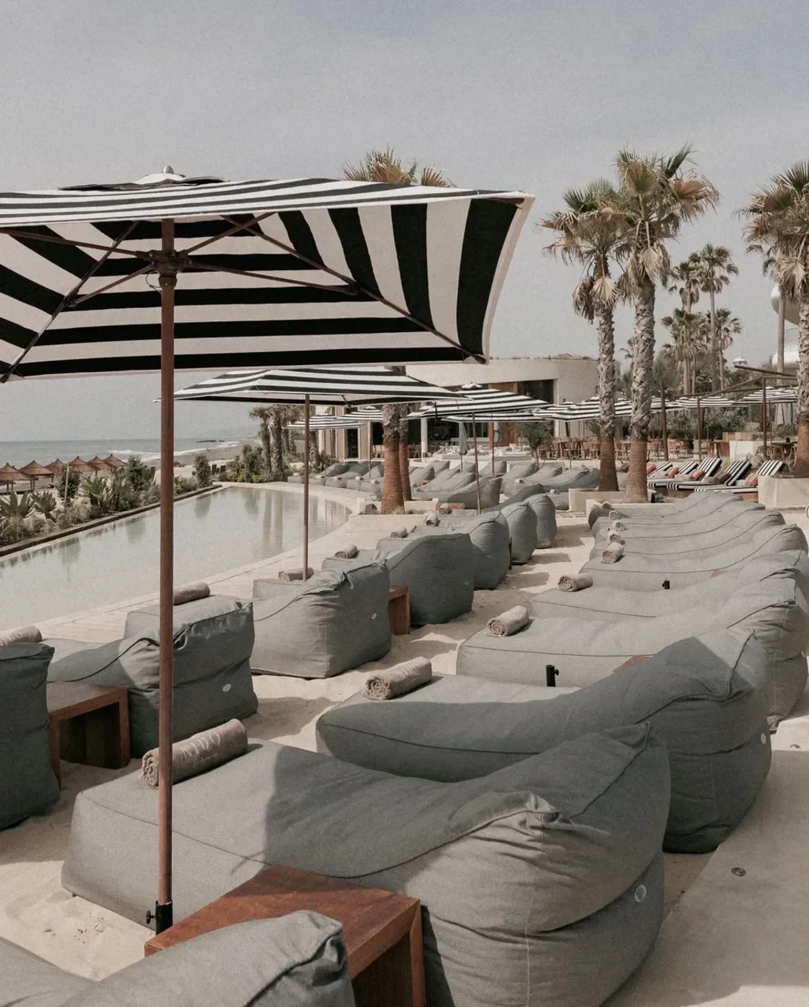 Relaxing beach scene at Nido Estepona, Marbella, featuring striped umbrellas and lounge seating.