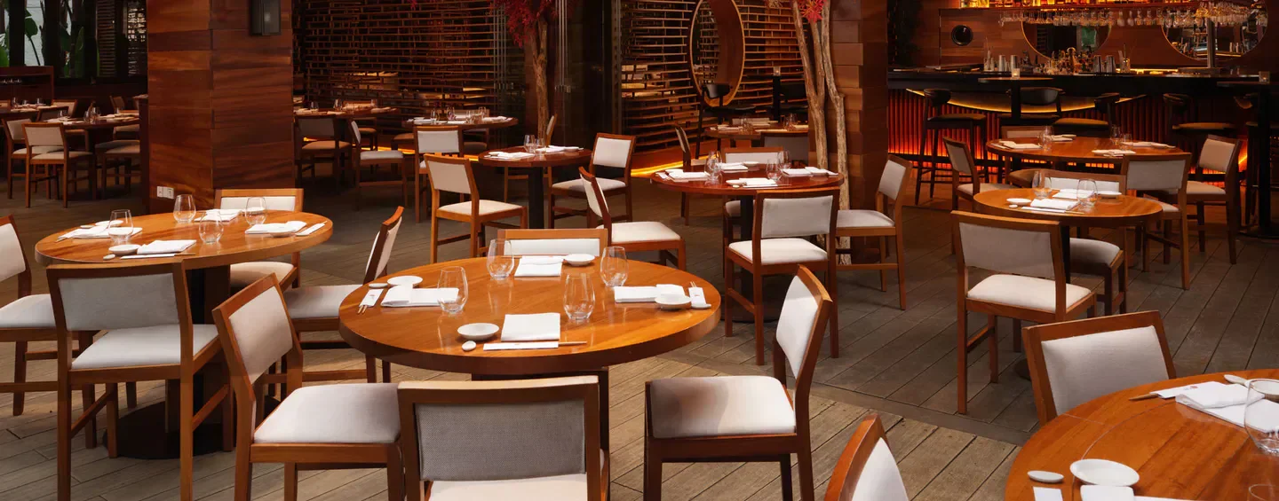 Interior of Nobu Marbella restaurant with wooden tables and elegant seating.