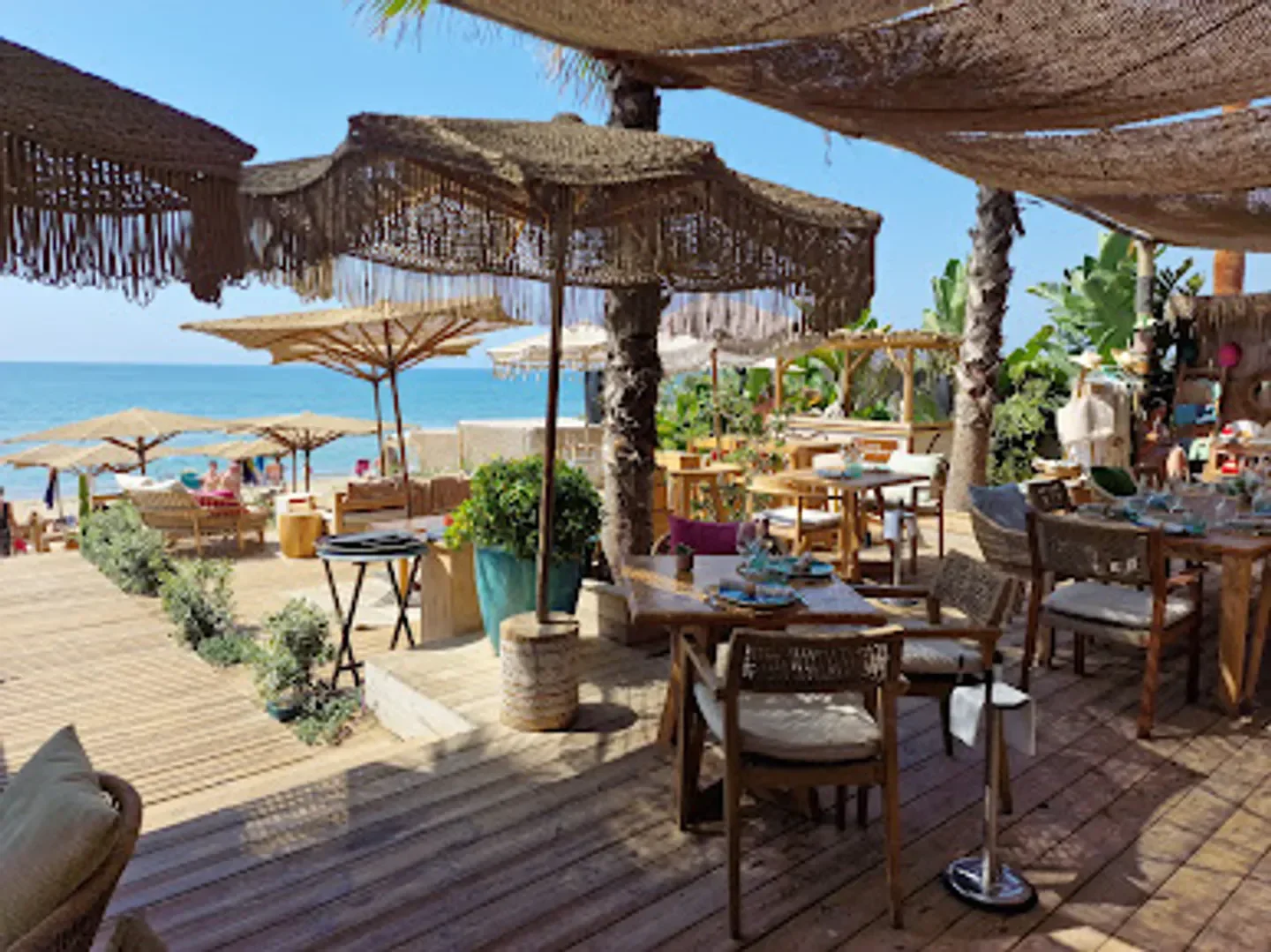 Nosso Beach Club in Marbella: Beachfront dining with umbrellas and ocean views.
