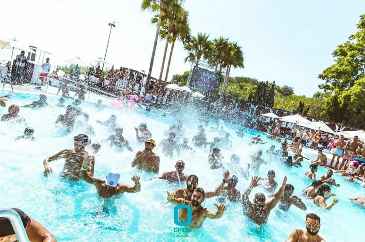 Energetic pool party at Opium Beach Marbella, with people splashing and having fun.